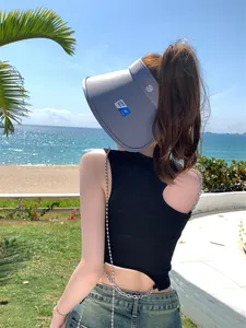 Vrouw met grijze zonneklep met brede rand op het strand voor zon- en UV-bescherming.