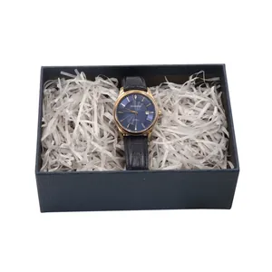 Carta di riempimento in rafia bianca in una scatola regalo blu con orologio di lusso