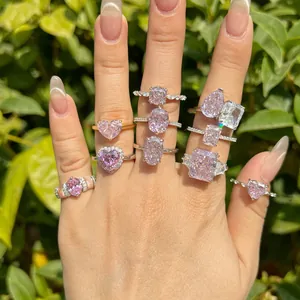 Collection of pink zirconia rings in various cuts on a hand against green background.