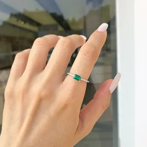 Vista dettagliata di un elegante anello in argento con gemma verde rettangolare sulla mano