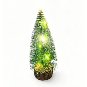 Mini tabletop Christmas tree with warm lights and snow-flocked needles on wooden base.