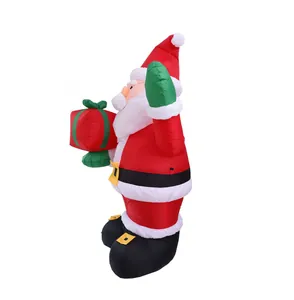 Side view of an inflatable Santa Claus carrying a red gift box on a white background
