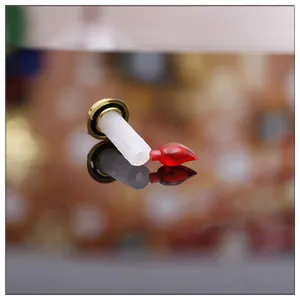 Vue détaillée d'une décoration de bougie de Noël miniature avec flamme rouge et base dorée.