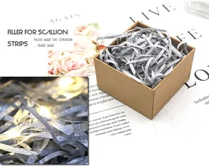 Macro detail showing silver glitter raffia filler inside a brown gift box.