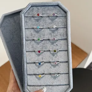 Close-up view of 12 vibrant colored birthstone rings displayed in a gray velvet tray