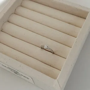 Close-up of elegant S925 sterling silver solitaire engagement ring in beige jewelry box.