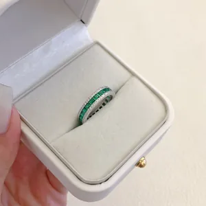 Primo piano di un elegante anello in argento con pietre verde smeraldo in una scatola bianca
