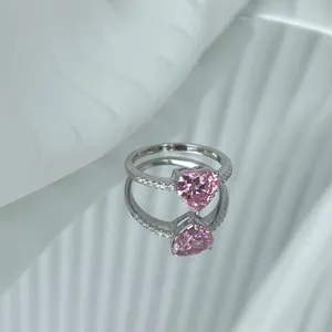 Gros plan d'une bague en argent avec pierre rose en forme de cœur sur un miroir.