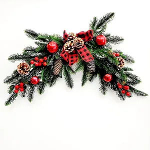 Christmas door swag with pine branches, red berries, cones and buffalo plaid bow
