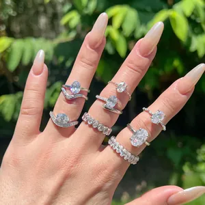 Detailed macro view of multiple sterling silver rings with oval ice cut zircon stones on hand