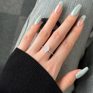 Detailed view of a silver ring with an oval ice-cut zircon stone on a manicured hand.
