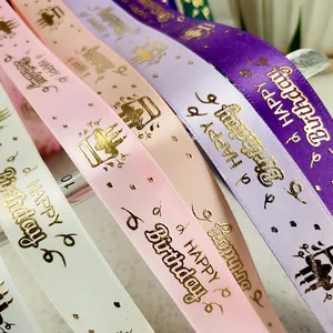 Macro detail of various colorful satin ribbons with gold foil HAPPY Birthday text.