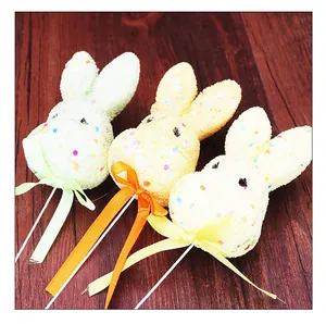 Detailed close-up of three colorful foam Easter bunny picks with ribbon bows on wood background
