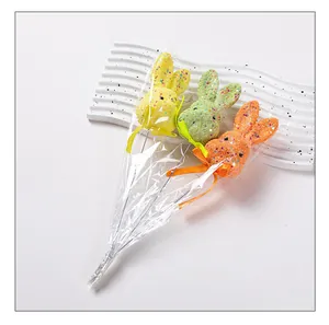 Macro shot of three colorful glittery foam bunny picks for Easter garden decoration.