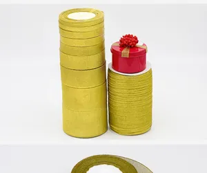 Stacks of premium gold metallic glitter ribbons with red gift box on white background