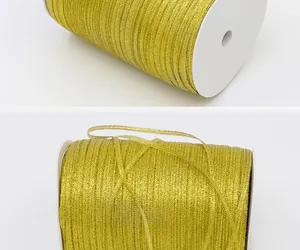 Close-up detail of golden metallic shimmering ribbon wound on a white spool