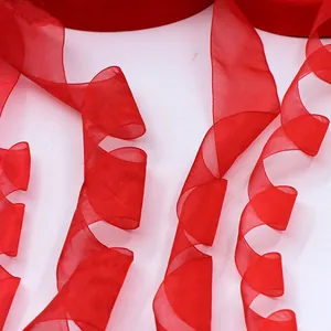 Nastro di organza rosso vibrante presentato in eleganti spirali su superficie bianca.