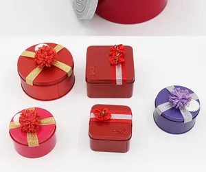 Assorted decorative metal gift tins with festive ribbons and pom-poms