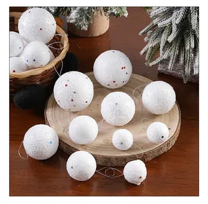 Variedad de adornos de bolas de espuma con purpurina blanca para Navidad en madera.