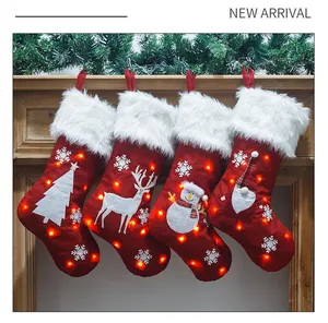 Calcetines de Navidad de lino rojo luminosos colgados en la chimenea con luces LED