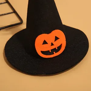 Detalle de un sombrero de bruja de Halloween para mascotas con cara de calabaza naranja.