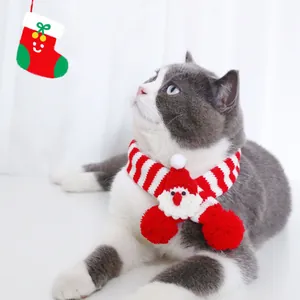 Gros plan d'une écharpe de Noël tricotée pour chat rayée rouge et blanc avec motif Père Noël