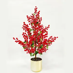 Künstliche rote Winterbeeren-Pflanze in einem goldenen Topf für festliche Wohndeko.