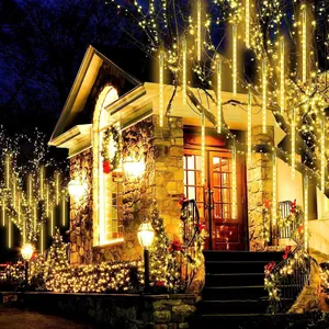 Close-up of warm yellow LED meteor shower lights hanging on outdoor trees at night