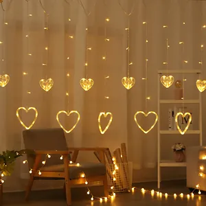 Warm white LED curtain lights featuring hanging hearts in a cozy indoor bedroom setting.