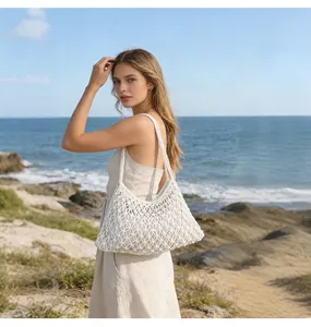 Borsa a spalla in rete di cotone bianco fatta a mano indossata su una spiaggia