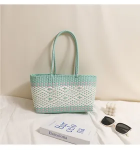 Vista dettagliata della borsa da spiaggia in plastica intrecciata menta e bianca con decori