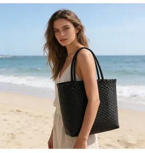 Stylish woven black plastic tote bag displayed in a relaxing beach lifestyle setting