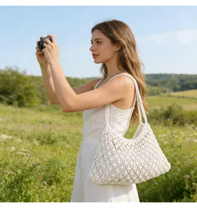 Borsa a tracolla in rete intrecciata a mano indossata da modella in un prato