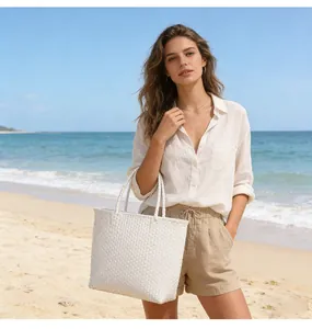 Large white woven plastic tote bag styled on a beach for a trendy summer holiday look