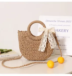 Cute semi-circular straw woven bag with lace bow and orange pom-poms