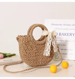 Close-up detail of semi-circular straw woven bag featuring a delicate white lace bow