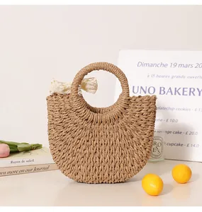 Close-up of a handmade semi-circular straw bag featuring a delicate white lace bow on handle