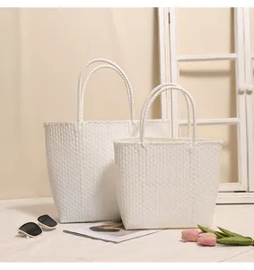 Lifestyle view of two white woven plastic tote bags in different sizes for beach use