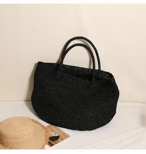 Detailansicht einer großen schwarzen gewebten Raffia-Stroh-Tragetasche für den Urlaub