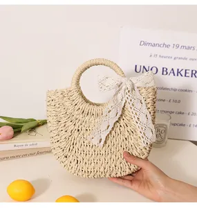 Detail view of a semi-circular handmade straw bag with a delicate white lace bow.
