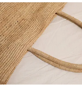 Detailansicht der dichten Raffia-Webung und der stabilen Griffe der Strandtasche aus Stroh