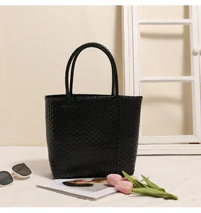 Detailed view of a black woven plastic tote bag in a stylish indoor lifestyle setting