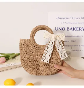 Close-up of a handmade semi-circular woven straw bag with a decorative white lace bow detail