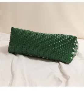 Vista dettagliata di una borsa a cesto in plastica intrecciata a mano verde e bianca.