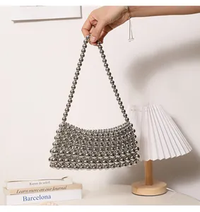 Silberne gewebte Achseltasche mit Metallperlen, die in einem stilvollen Raum gehalten wird