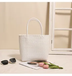 Elegant white woven plastic tote bag styled with seaside vacation lifestyle props