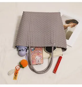 Large gray woven plastic tote bag filled with daily essentials in a top macro view