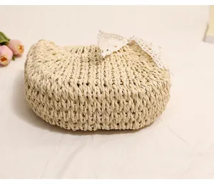 Close-up detail of a semi-circle woven straw bag with a delicate white lace bow ornament