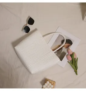 Elegant white woven plastic tote bag shown from above with trendy beach accessories