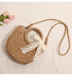Close-up of a semi-circular straw woven bag with an elegant white lace bow